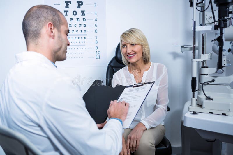 Optometrista maschio che parla con paziente femminile immagine stock libera da diritti