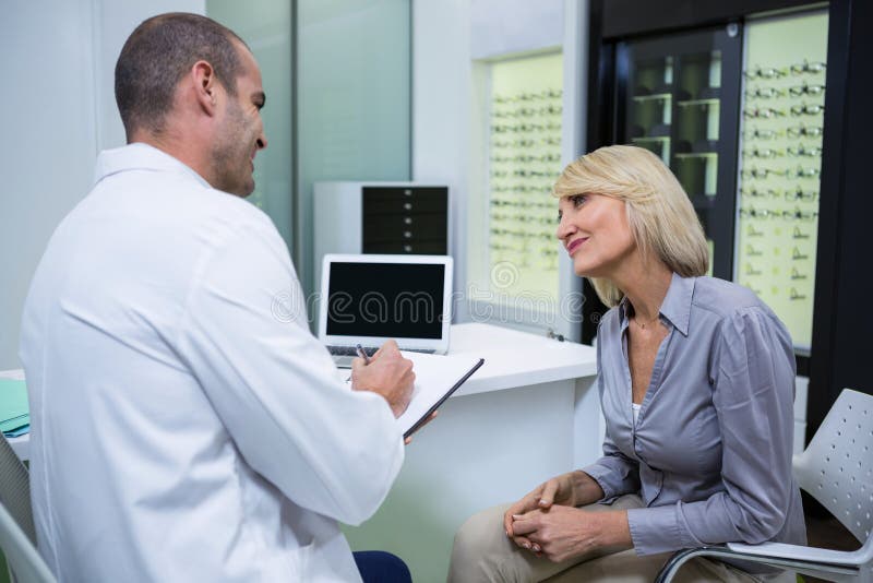 Optometrista maschio che parla con paziente femminile fotografie stock