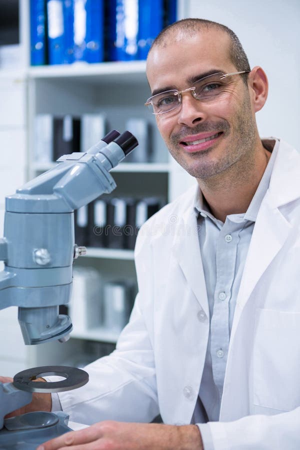 Optometrista maschio sorridente con il microscopio fotografie stock