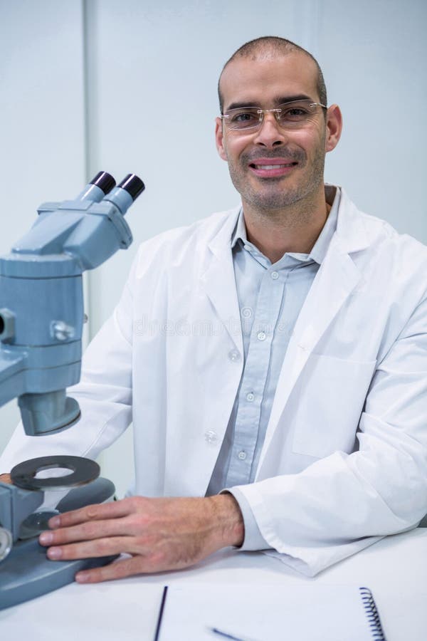 Optometrista maschio sorridente con il microscopio fotografia stock libera da diritti