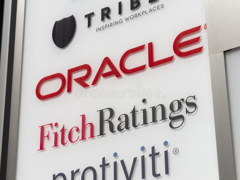 Oracle Corporation and Fitch Ratings Logo Sign. On the entrance of an office complex. American computer technology company and a credit rating agency