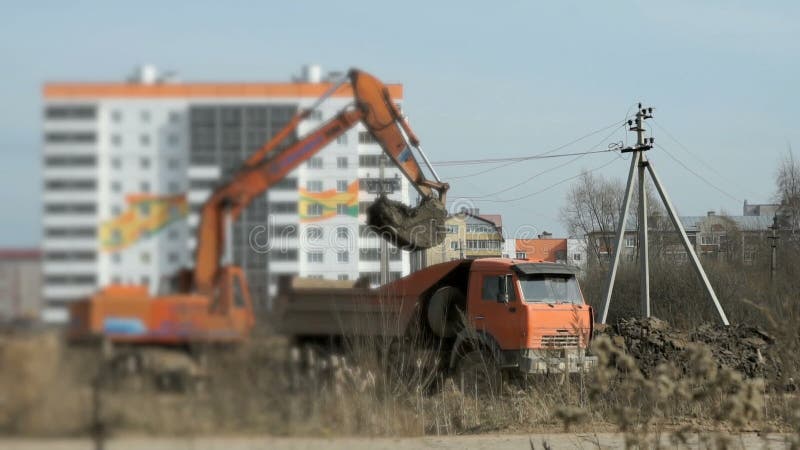 Orange Bagger lädt den Lehm in Kipplaster