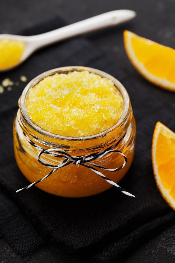 Orange body scrub with sugar and coconut oil in glass jar on vintage background. Homemade cosmetic for peeling and spa care