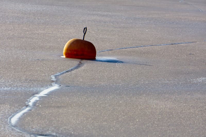Orange buoy on a frozen lake stock images