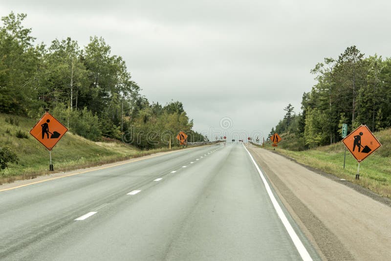 Orange byggnadsarbetaretecken på vägen in i avståndet på trans. Kanada royaltyfri foto Orange byggnadsarbetaretecken på vägen in i avståndet på trans. Kanada royaltyfri foto