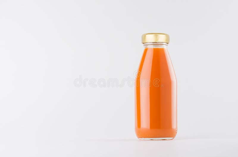 Orange carrot juice in glass bottle with gold cap mock up on white background with copy space, template for packaging, advertising