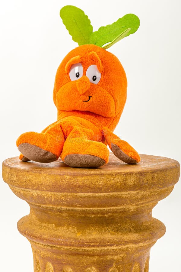 Orange Carrot Plush Toy Sitting on a Pillar Against White Studio ...