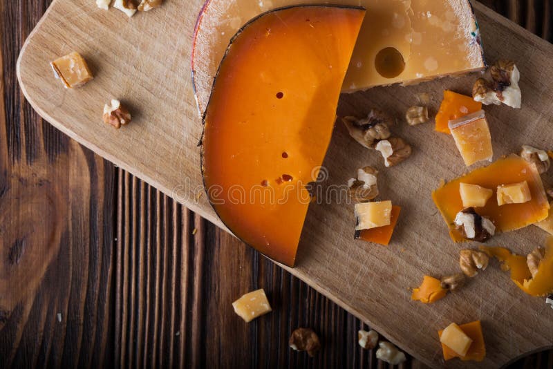 Orange cheese on a wooden board with nuts stock photography Orange cheese on a wooden board with nuts stock photography