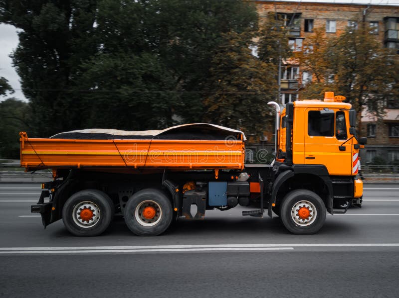 Naranja la ciudad utilidad camión en movimienot sobre el carreteras.