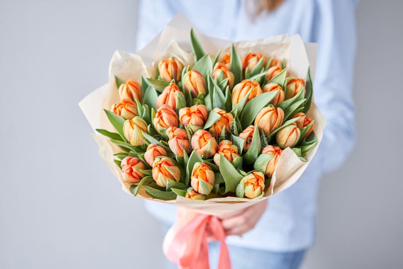 Orange color tulips in woman hand. Young beautiful woman holding a spring bouquet. Bunch of fresh cut spring flowers in