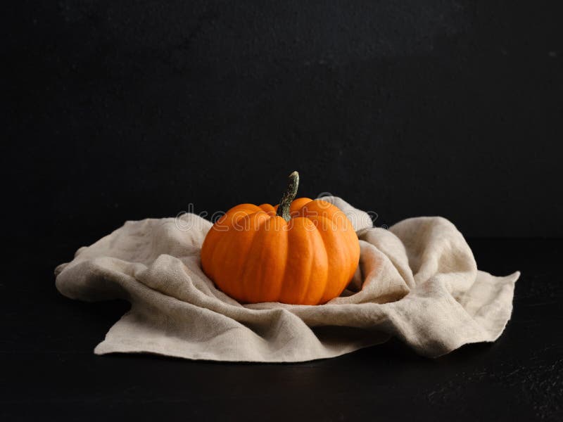 Orange Colored Autumn Pumpkin on a Napkin Against Black Background with