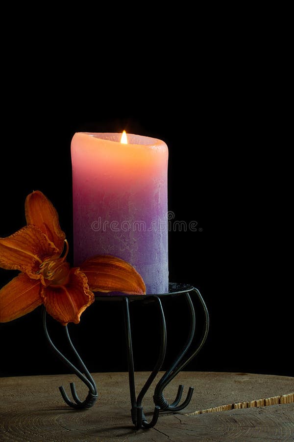 Orange daylily and burning purple candle against black background. Fresh flower head of orange daylily and burning purple candle against black background royalty free stock photos Orange daylily and burning purple candle against black background. Fresh flower head of orange daylily and burning purple candle against black background royalty free stock photos
