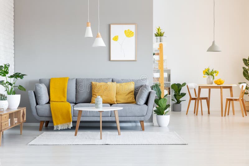 Orange blanket on grey sofa in modern apartment interior with poster and wooden table. Real photo. Orange blanket on grey sofa in modern apartment interior with poster and wooden table. Real photo