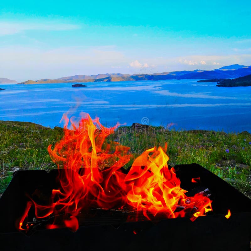 Orange flames, a fire burning in a black iron grate against the lake. royalty free stock photo Orange flames, a fire burning in a black iron grate against the lake. royalty free stock photo