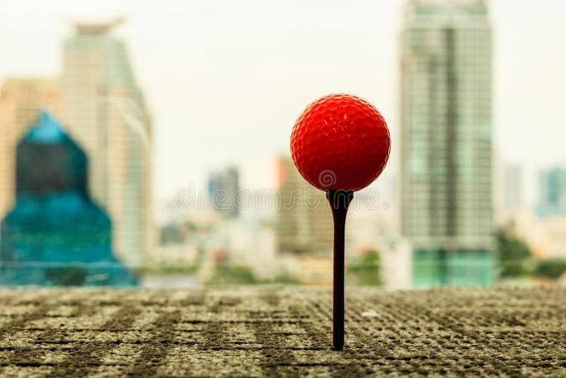 Orange Golfball auf T-Stück hinter Stadtbildszene im Büro Gehen Sie lizenzfreies stockbild Orange Golfball auf T-Stück hinter Stadtbildszene im Büro Gehen Sie lizenzfreies stockbild