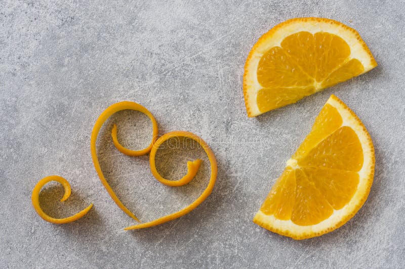 Orange Half Circle Slices and Peeled Skin Curls on Stone Grey