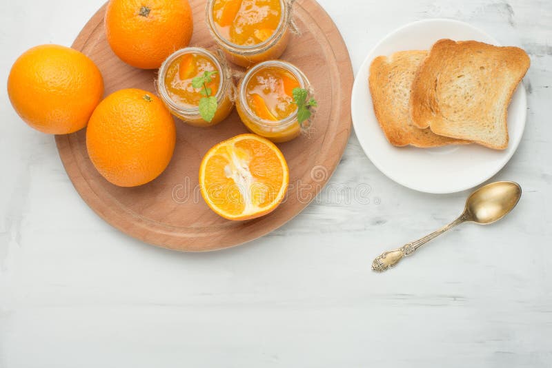 Orange jam in a glass jar on a light background with toasts. With empty space for writing stock photography Orange jam in a glass jar on a light background with toasts. With empty space for writing stock photography