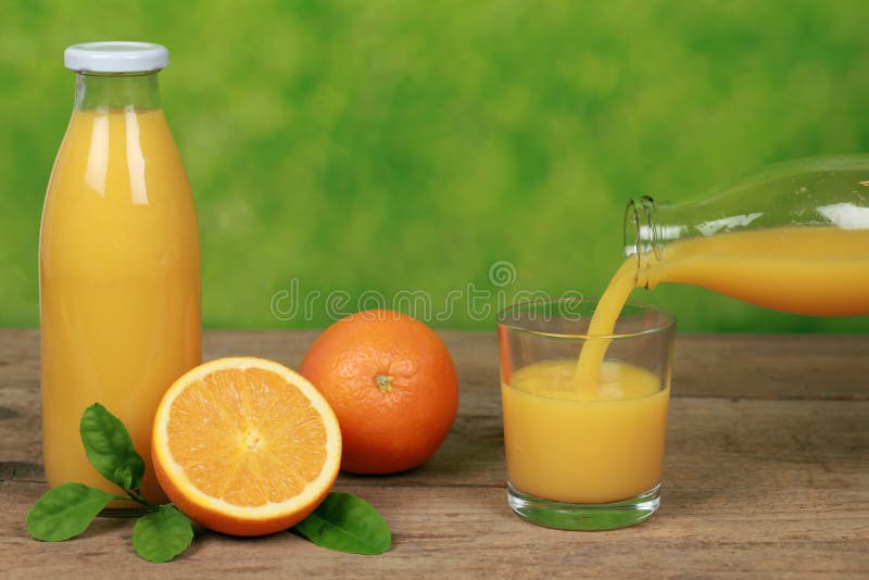 Fresh orange juice is pouring from a bottle into a glass