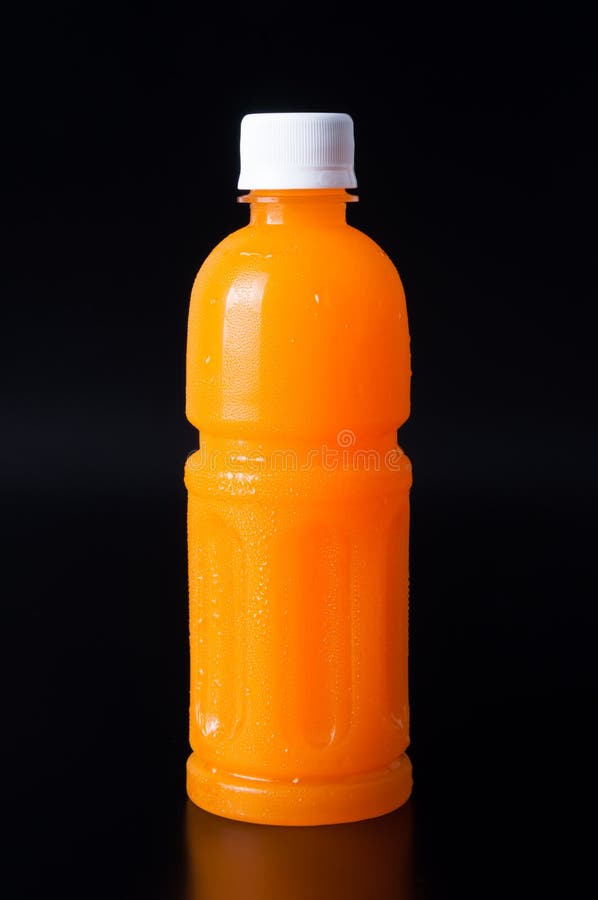 Orange juice in a bottle and orange on black