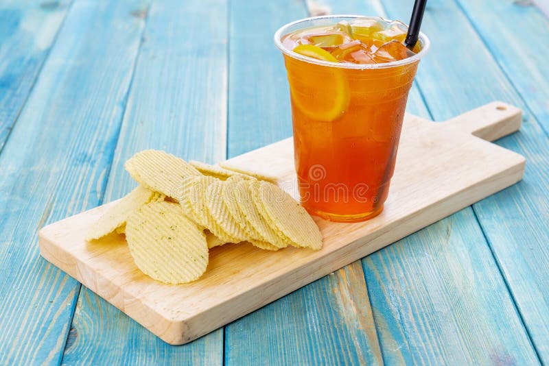 Orange Juice with Chips Potato Chips with Orange Juice on Blue Wood