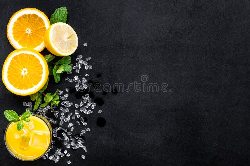 Orange juice and citrus cocktails. Juice in glass near cut orange and lemon, crushed ice, green mint on black background