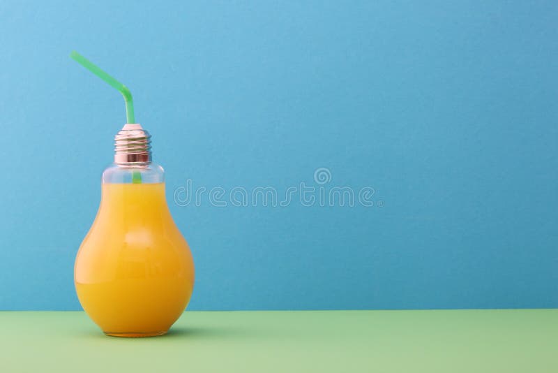 Orange juice in light bulb glass on bright blue  background