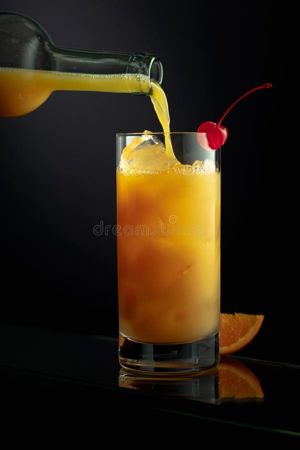 Orange juice is poured into a tall glass with ice