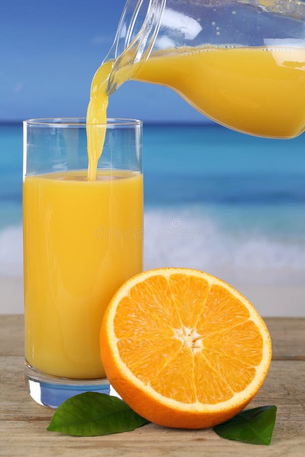 Orange juice pouring into a glass on the beach while on vacation. Orange juice pouring into a glass on the beach while on vacation