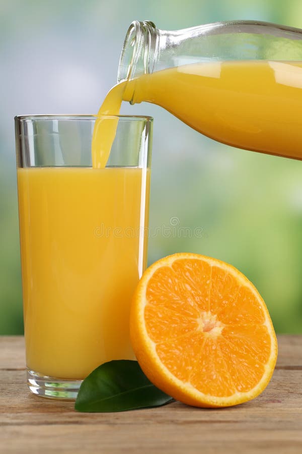 Orange juice pouring from oranges fruits into a glass in summer