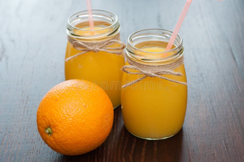 Orange Juice and Whole Orange in Two Jars Rustic Style Side View, Copy