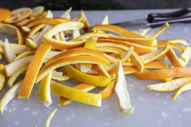 Slices of orange and lemon peels on a cutting board for the preparation of making them into candied peels. Slices of orange and lemon peels on a cutting board for the preparation of making them into candied peels