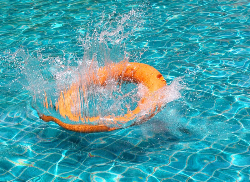 Orange life buoy splash water in the blue swimming pool