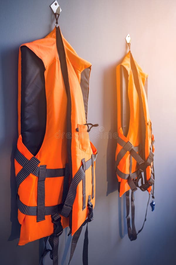 Orange Life Jackets Hanged on Plain Grey Wall by Swimming Pool for ...