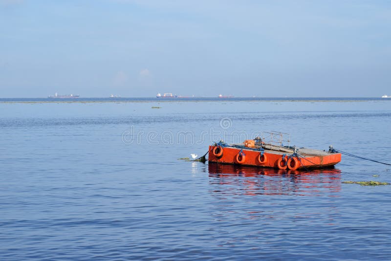 Orange malte Metalllastkahn verankert entlang Ozeanbucht lizenzfreie stockfotografie Orange malte Metalllastkahn verankert entlang Ozeanbucht lizenzfreie stockfotografie