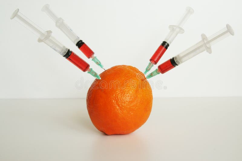 Orange and medical syringes. GMO fruit.