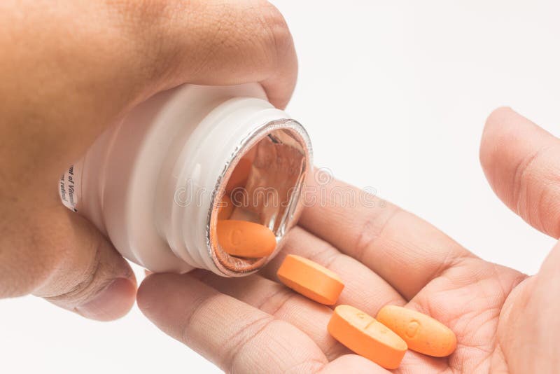 Orange Medicine Capsules in a Spoon on a White Background Stock Image