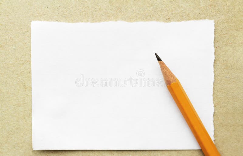 Orange pencil on a scrap of empty paper for notes on a cardboard background, concept back to school