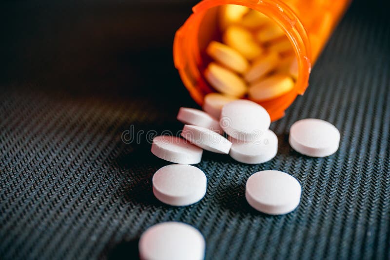 Orange Pill Bottle with Scattered White Pills on a Black Textured