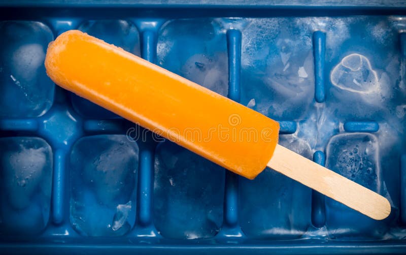 Orange popsicle on tray of ice cubes