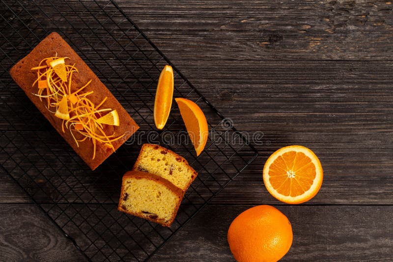 Orange pound cake on a cooling rack alongside oranges on dark vintage wood background, Flat lay. Copy space stock photo Orange pound cake on a cooling rack alongside oranges on dark vintage wood background, Flat lay. Copy space stock photo