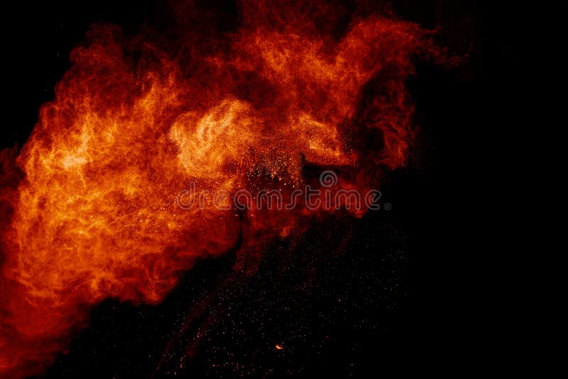 Orange powder splattered on black background. Abstract dust cloud backdrop royalty free stock photo.