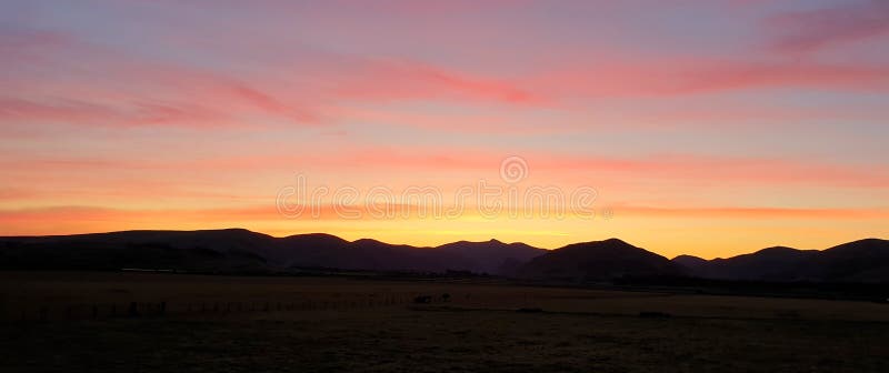 Orange red fiery sunrise sunset over silhouette mountain landscape