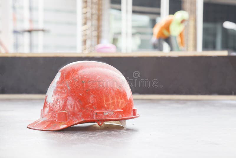 Orange safety helmet in construction with worker background. stock photo Orange safety helmet in construction with worker background. stock photo