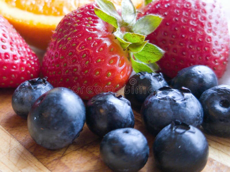 Orange Stawberry-Blaubeerfrüchte auf hölzernem Schneidebrett stockbild Orange Stawberry-Blaubeerfrüchte auf hölzernem Schneidebrett stockbild