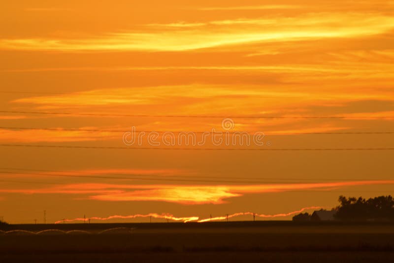 Orange sunset and cloudy skies over Nebraska fields