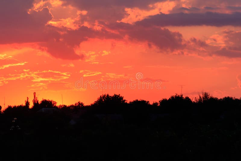 Orange Sunset Over Silhouettes of Village and Trees Stock Photo Image