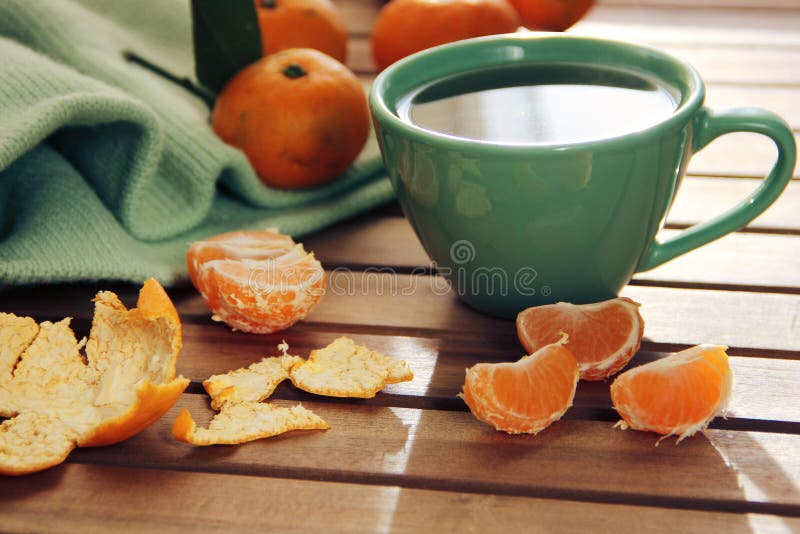 Orange tangerine and mandarin slices, green cup of tea