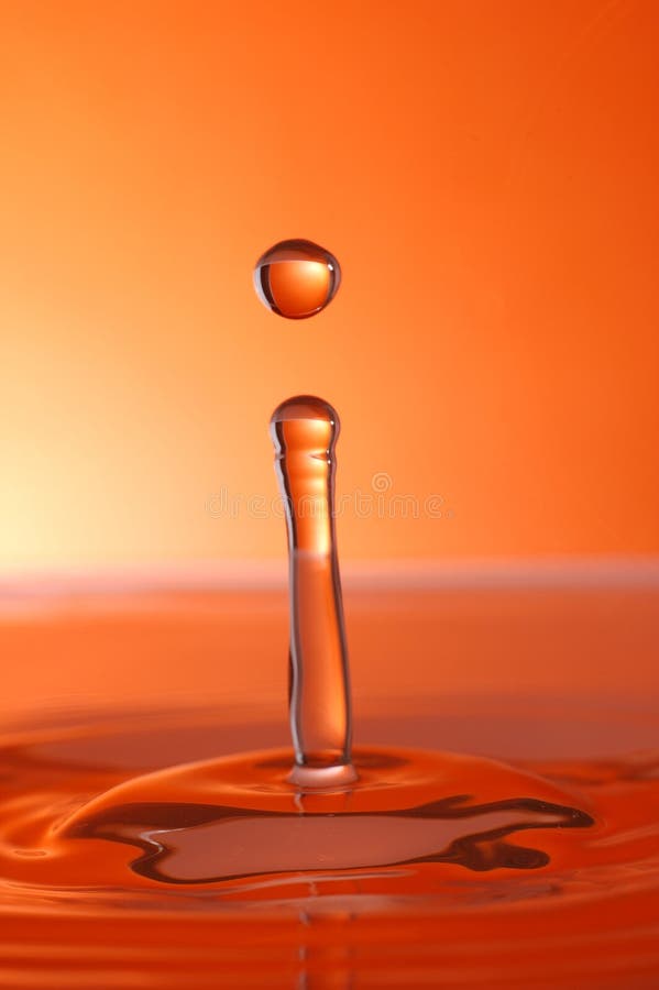 Water droplet over orange background, high speed photography. Water droplet over orange background, high speed photography.