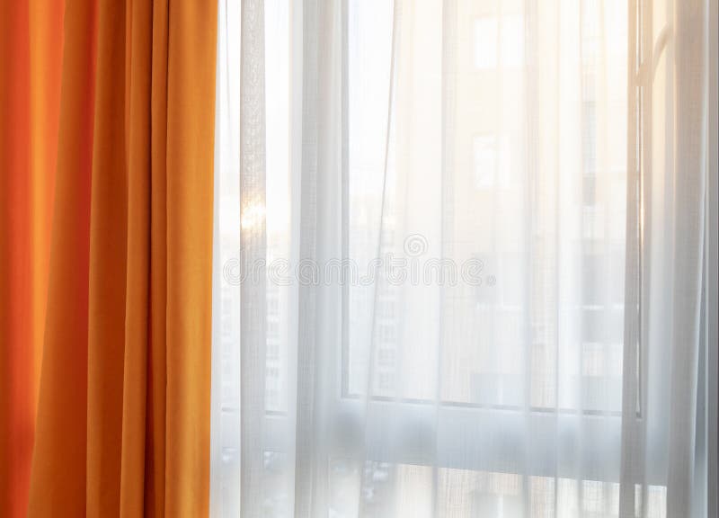 Orange and white curtains against sunlights through window