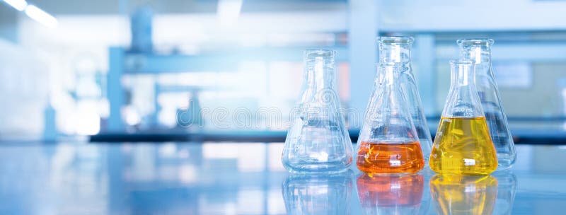 Orange yellow solution in science glass flask win blue chemistry laboratory banner background. Orange yellow solution in science glass flask win blue research